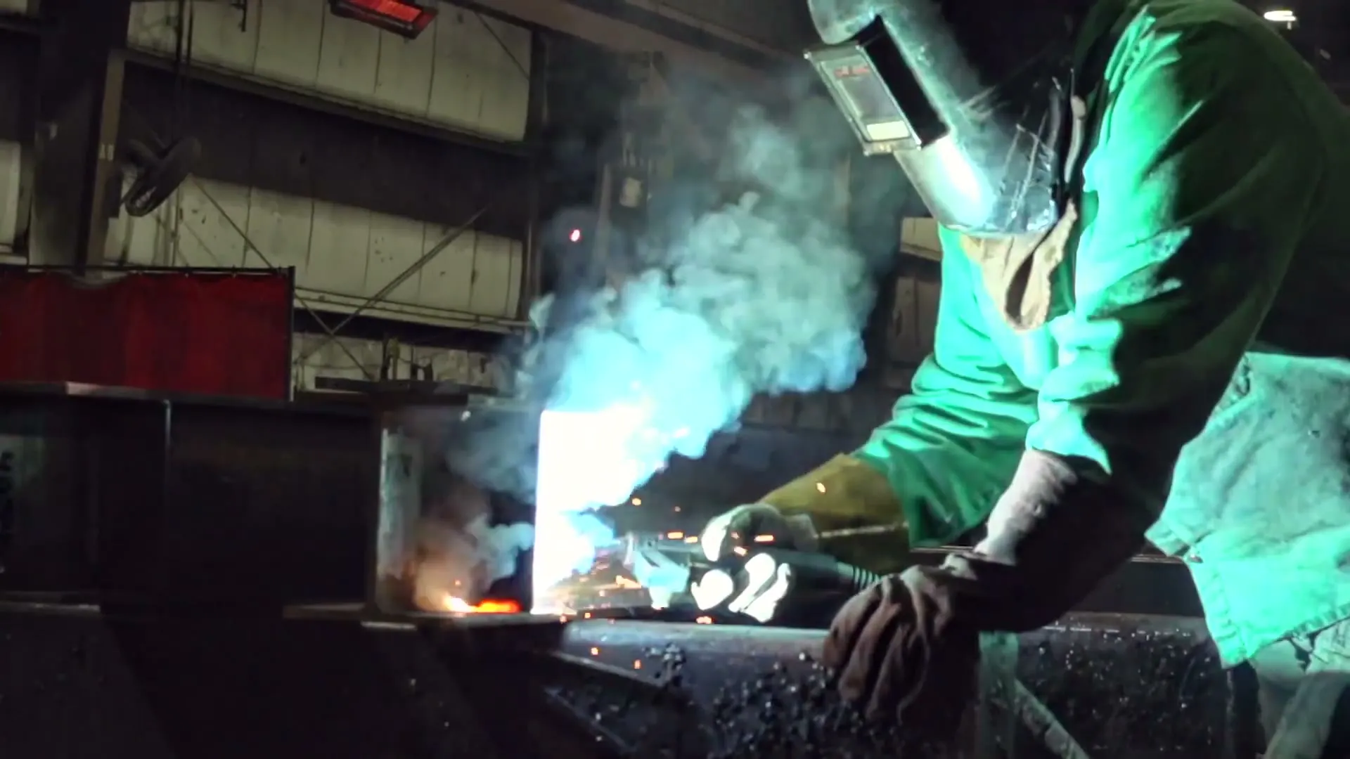 A Garbe Iron Works welder in a welding hood joining steel, sparks and smoke rising from the arc
