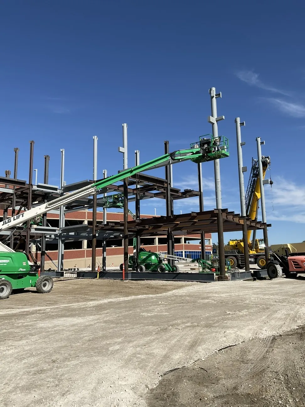 Aurora University Learning Commons: boom lifts and a crane setting steel at the corner of the frame