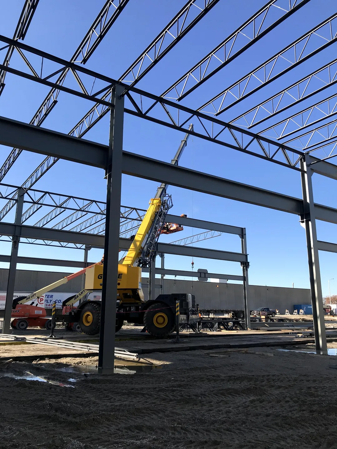 Bulldog Cartage: a rough-terrain crane setting steel between the columns and joist girders