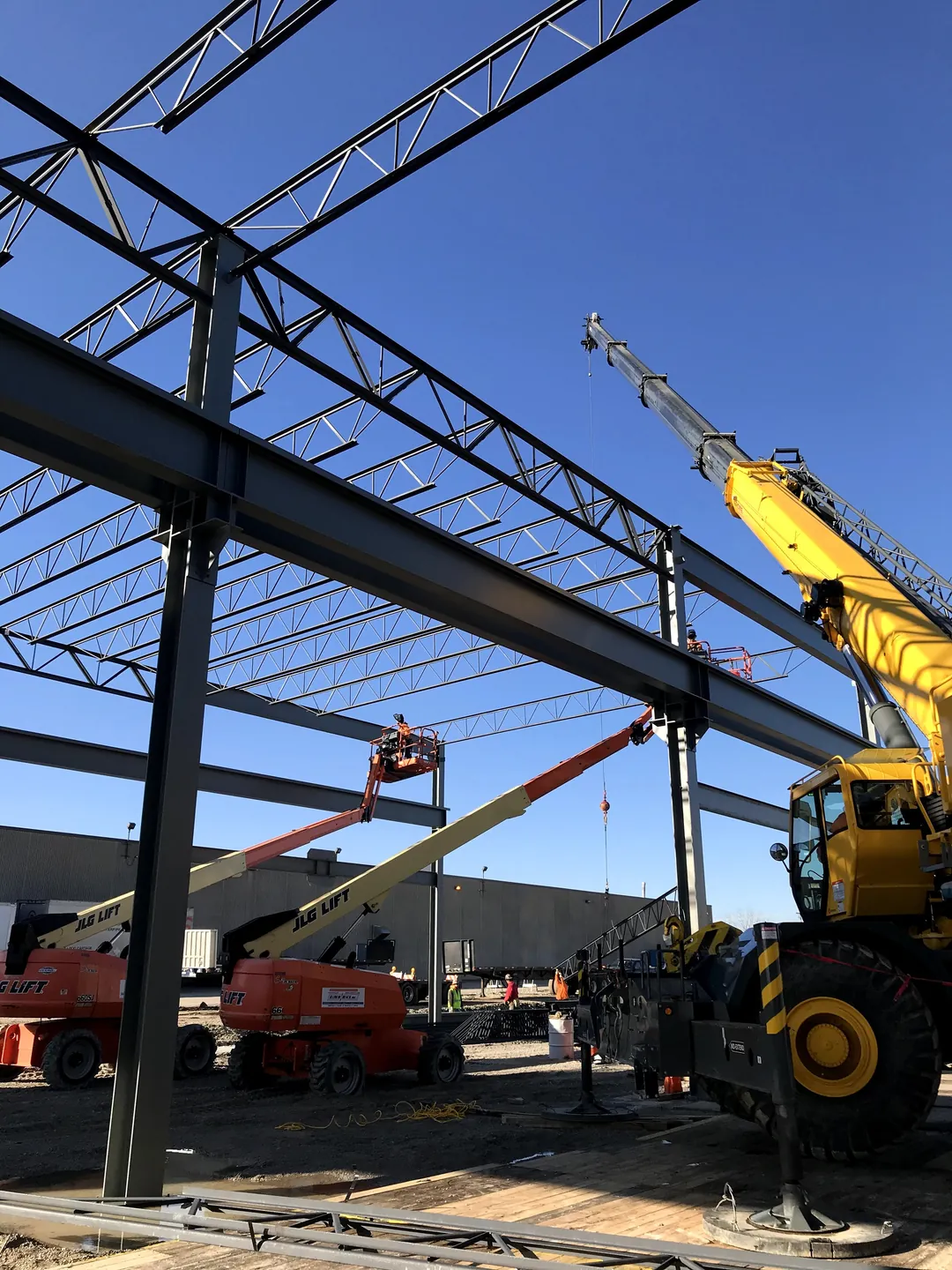 Bulldog Cartage: a crane and boom lifts at work under the joist girders