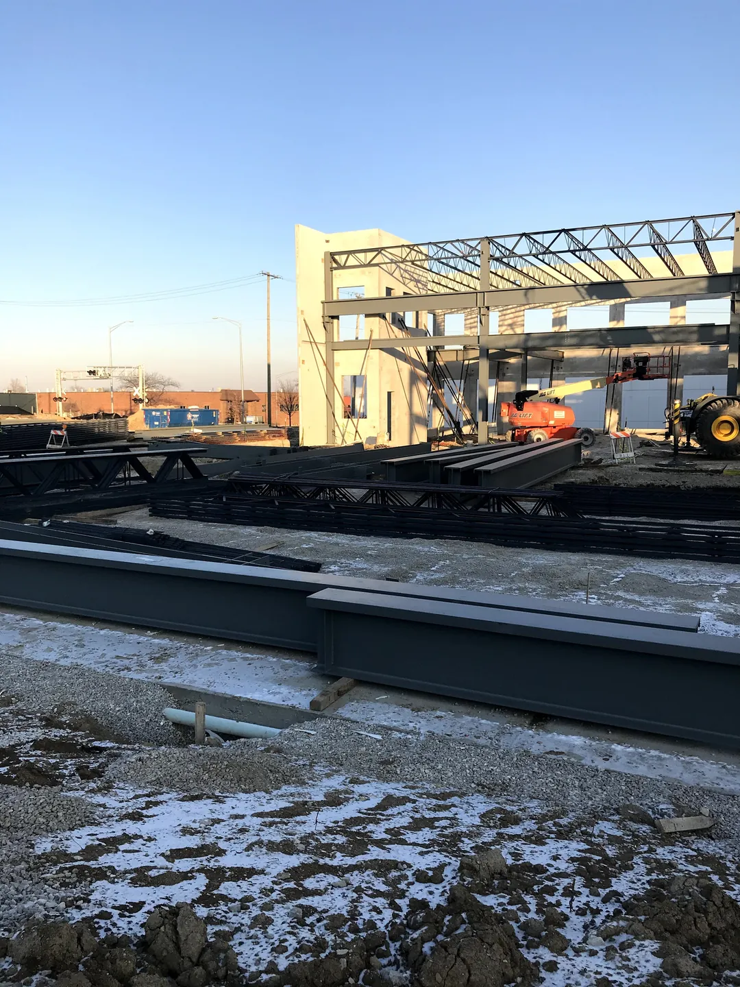 Bulldog Cartage: steel members staged on frozen ground in front of the frame