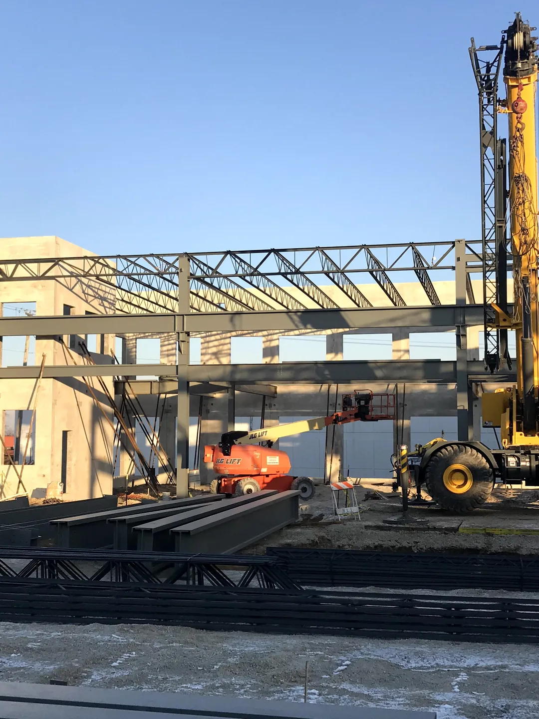 Bulldog Cartage: a crane and boom lift beside the office-end framing and tilt-up panels