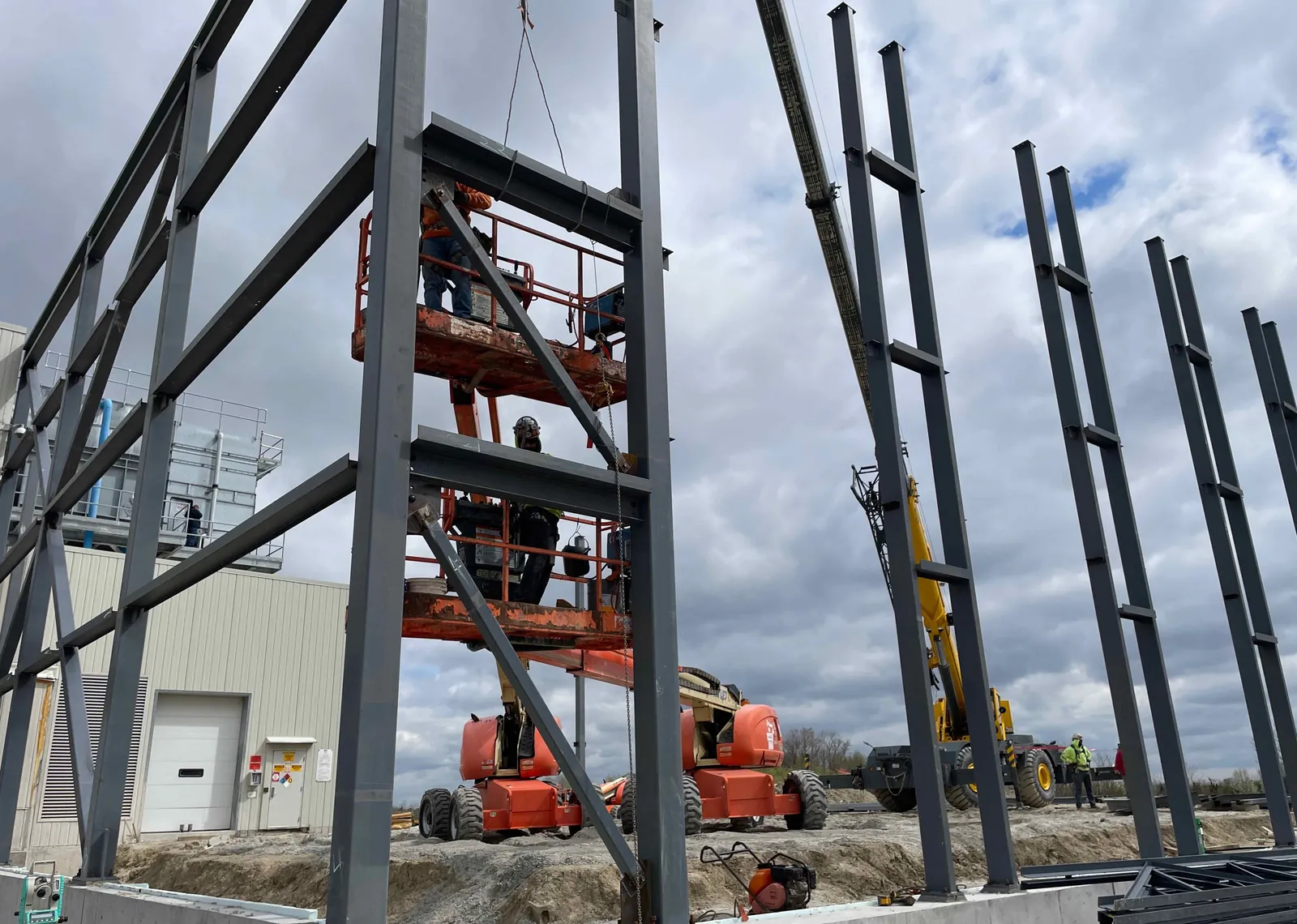 DOT Foods: ironworkers on lifts connecting steel between the columns