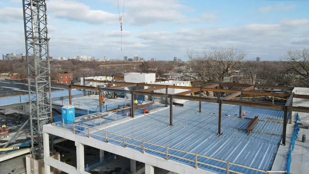 Project HOOD: steel columns and beams going up on the decked roof, with a tower crane at left