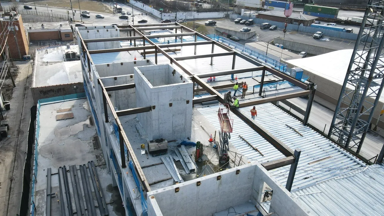 Project HOOD: aerial view of beams around the concrete cores, with ironworkers on the deck