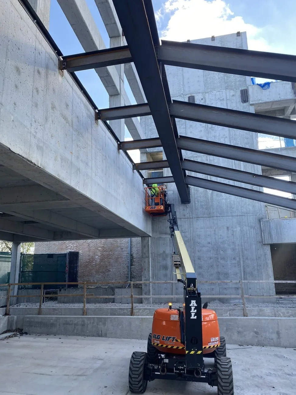 Project HOOD: an ironworker on a boom lift connecting beams to the concrete structure