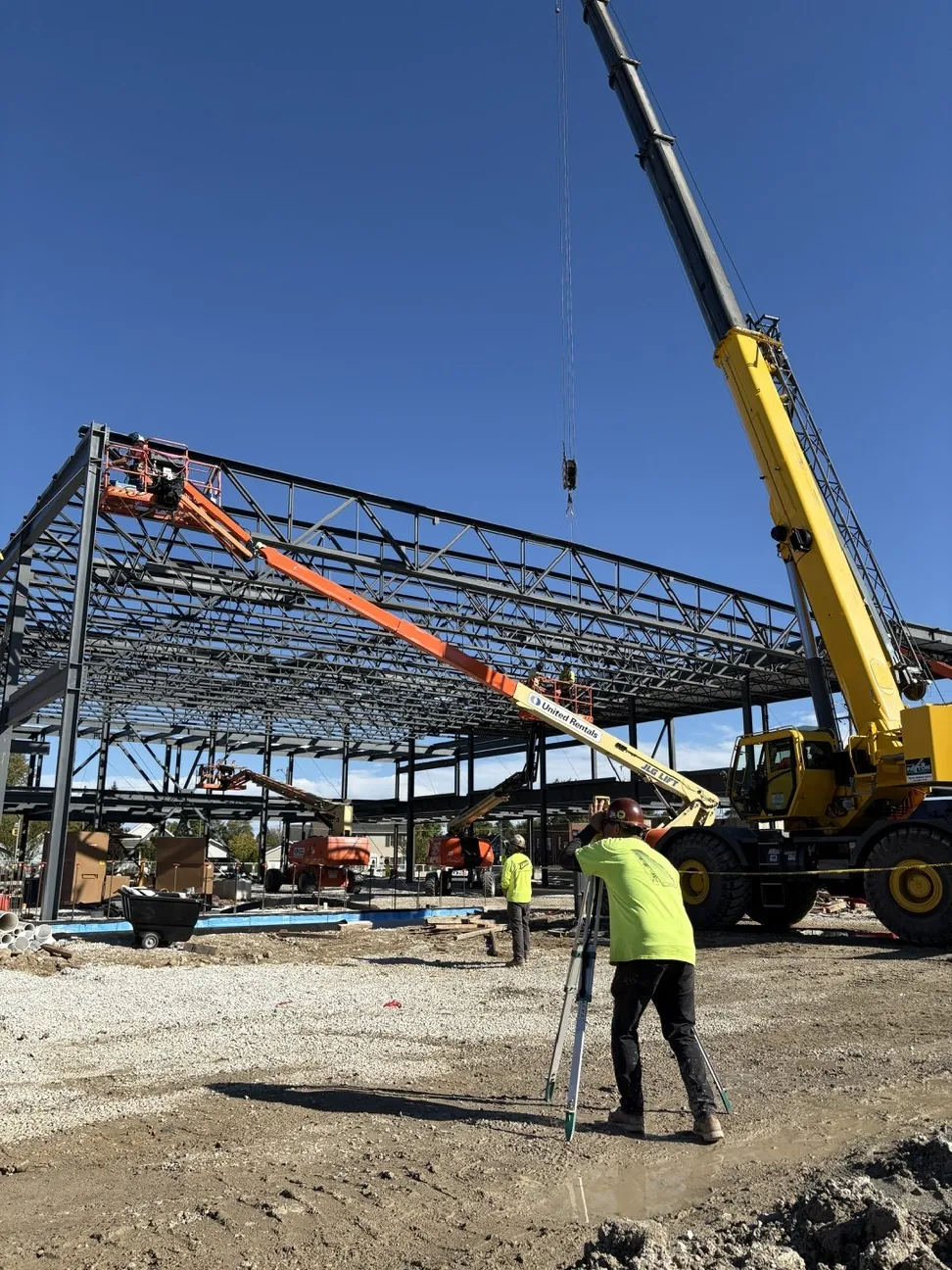 Lincoln King Center: a worker with a survey instrument while a crane sets roof steel