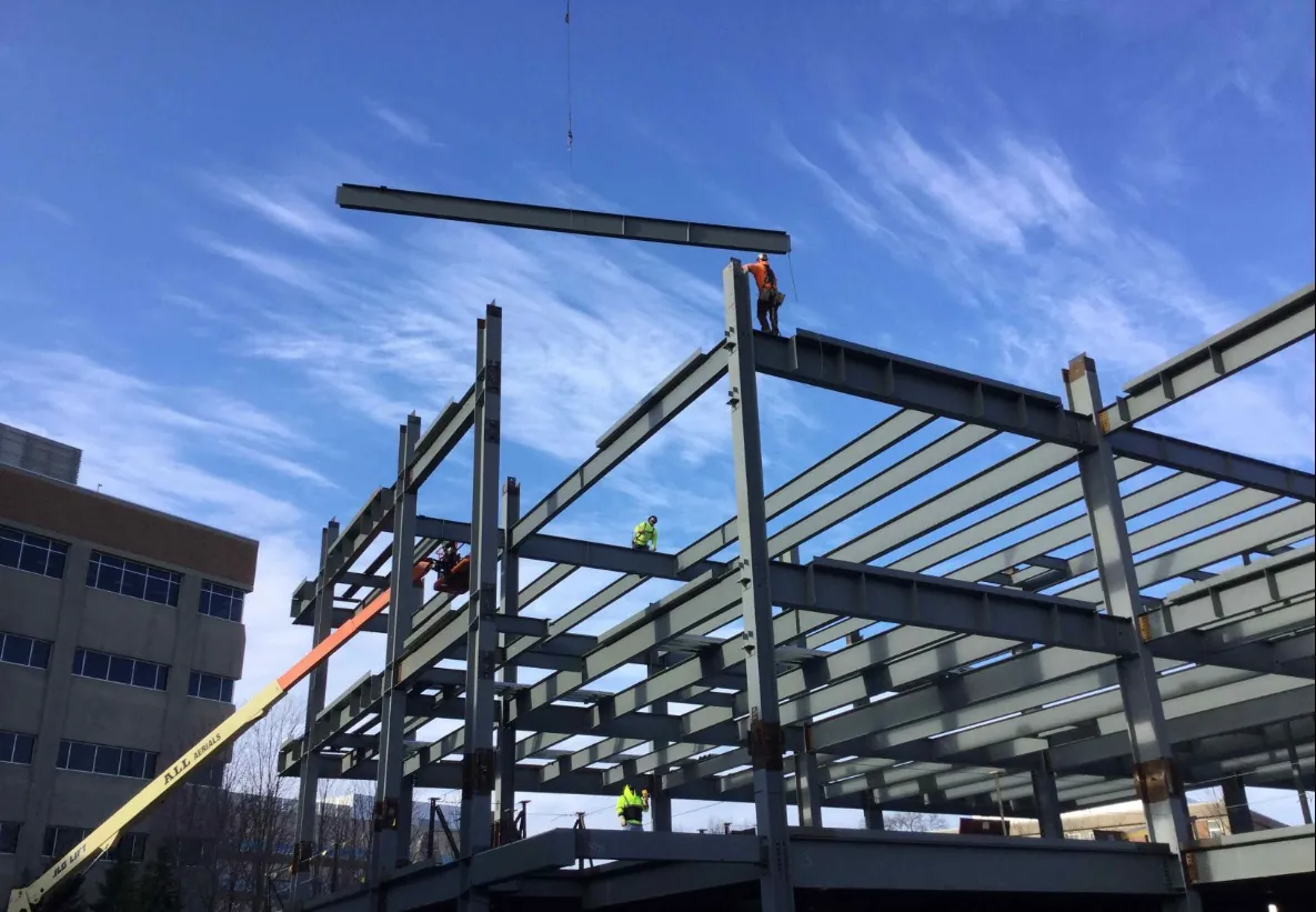 Midwestern University Support Services Building: ironworkers setting a beam on the upper level of the frame