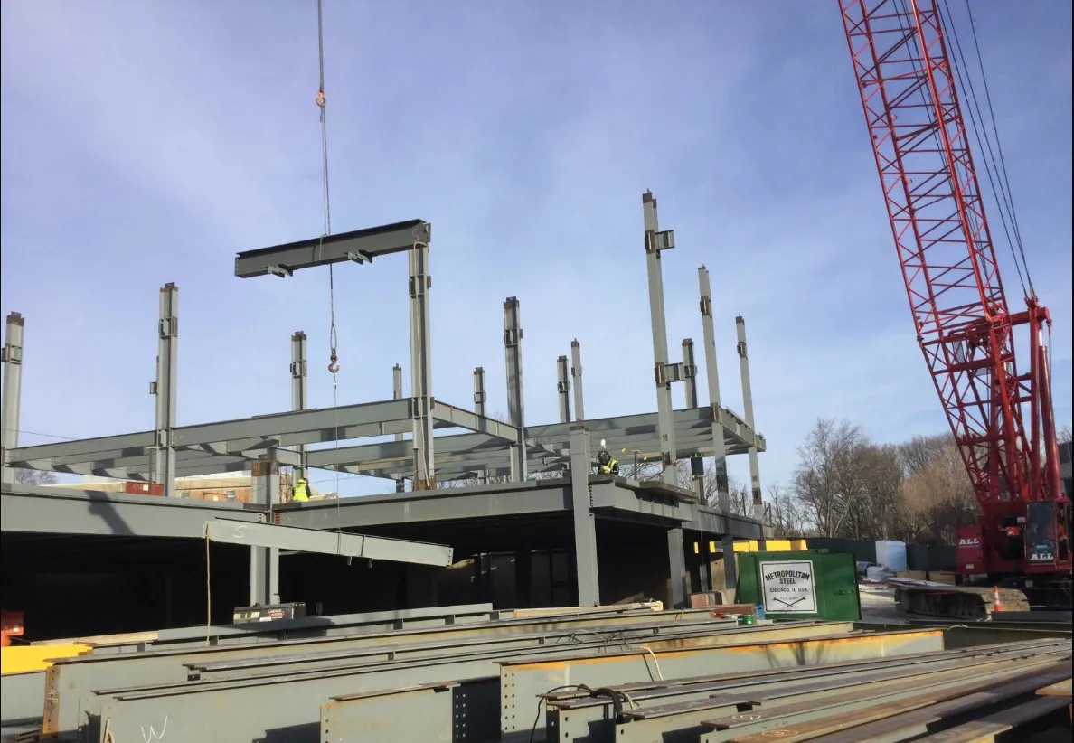 Midwestern University Support Services Building: columns going up beside a crawler crane, with steel staged in the foreground