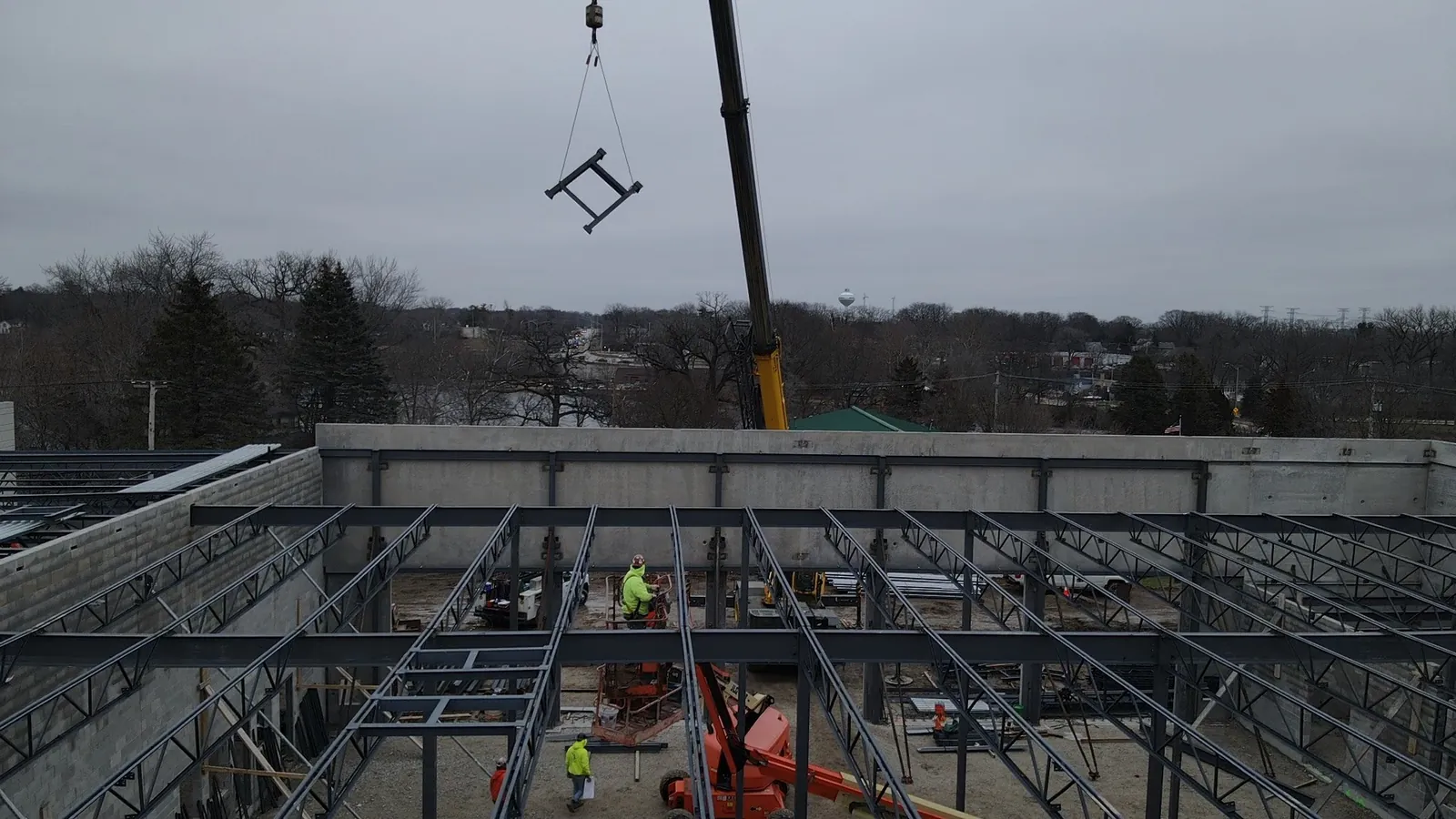 North Aurora Fire District Headquarters: a crane lifting steel over the floor framing inside the precast walls