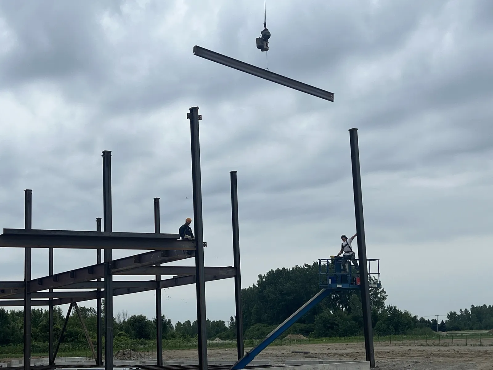 Northwest Community Cancer Center: a beam on the crane line, with ironworkers waiting on the columns