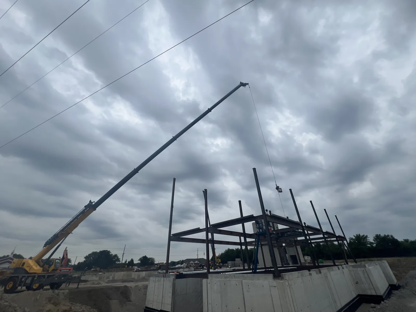 Northwest Community Cancer Center: a crane lifting steel onto the frame under a cloudy sky
