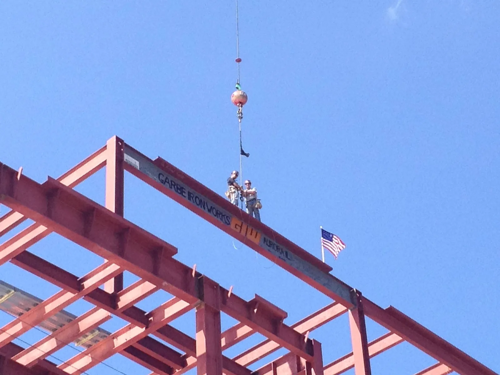 A steel beam being lifted into place on a building frame