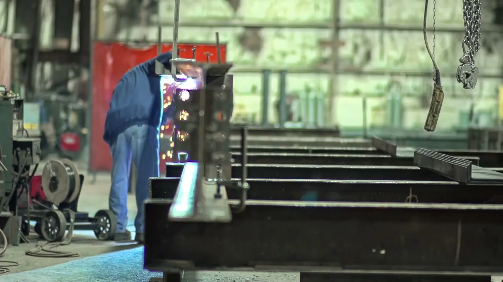 Welder working between fabricated steel members